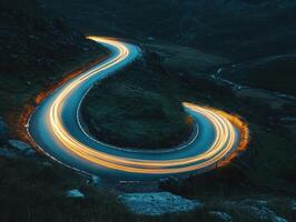 Winding road illuminated by car lights in a mountainous landscape photo