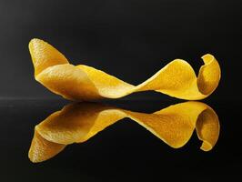 Yellow citrus peel sculpture on black reflective surface photo