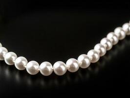 Elegant pearl necklace displayed on dark surface photo