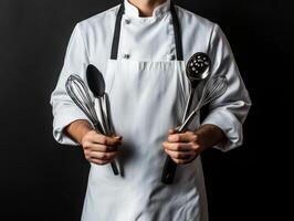 Chef holding various cooking utensils in a kitchen setting photo