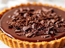 Chocolate tart topped with chocolate shavings on a marble surface photo