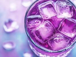 A glass filled with a vibrant purple drink sits on a colorful surface photo