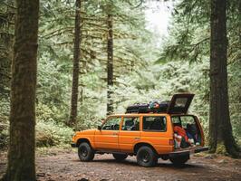 Orange SUV parked in a dense forest during a camping trip photo
