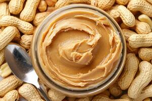 Peanut butter jar surrounded by peanuts on a wooden table photo