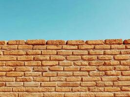 Brick wall under clear blue sky in a sunny setting photo