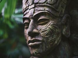 Stone sculpture of a carved figure in a lush green setting photo