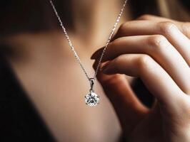 Elegant hand holding a diamond pendant necklace in soft lighting photo