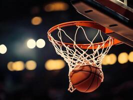 Basketball swishes through hoop in an indoor arena during evening game photo