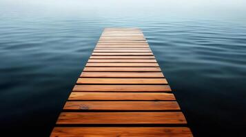 Wooden footbridge leading into a calm lake on a foggy day photo