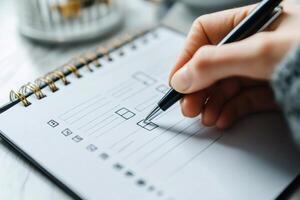 Woman checking boxes on checklist using pen in notebook photo