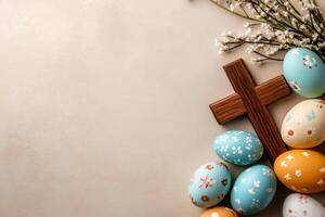 Easter eggs with wooden christian cross and spring flowers creating festive border on beige background photo
