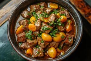 Tasty beef stew with apricots and fresh parsley in rustic bowl photo