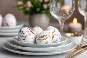 Easter eggs decorated with blooming sakura and birds resting on branches are arranged on plates for a festive table setting photo