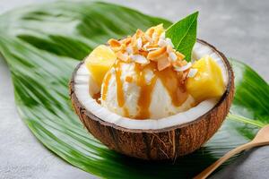 Coconut ice cream with pineapple and caramel topping resting on tropical leaf photo