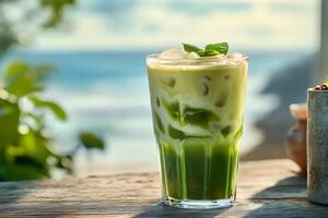 Iced matcha latte sitting on table with ocean view in background photo