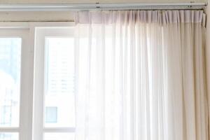 Soft white curtains drape elegantly over window, allowing gentle light to filter through, creating serene atmosphere photo
