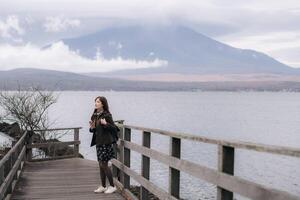 Japanese woman smiles in awe as she witnesses the fantastic view of Mount Fuji from a balcony. An image of relaxation and enjoyment in the lap of nature. photo