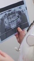 hembra dentista análisis dos rayos X a detectar cambios y hacer un preciso diagnóstico para el paciente. video