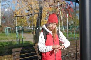 young sportive caucasian woman waiting for a bus on the glass bus stop photo