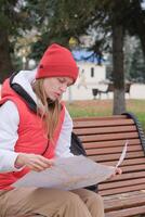 tourist holding map exploring new city and using phone sitting in the park photo
