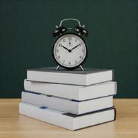 An alarm clock sits on top of a stack of books photo