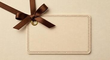 Blank card with brown ribbon and bow on beige background photo