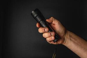 Hand holding a black flashlight in a dark setting photo