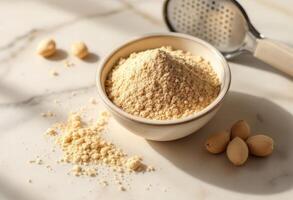 Bowl of nut powder on white surface with soft sunlight and scattered nuts. photo