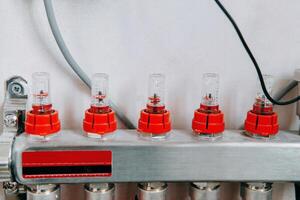 Water valve manifold with red caps aligned in row, highlighting the intricate design. Used for efficient control and distribution of water flow in plumbing systems. photo