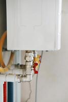 Close-up view of water heater pipes and valves in anutility room, featuring colorful connectorsd tubes. Essential components for heating system maintenance and operation. Gas boiler taps photo