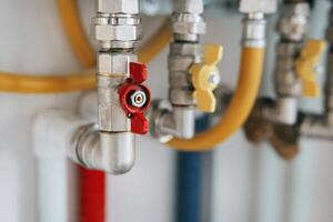 Close-up view of water heater pipes and valves in a utility room, featuring colorful connectors and tubes. Essential components for heating system maintenance and operation. Gas boiler tap photo