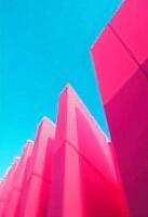 Abstract pink geometric structures reach skyward against a vibrant blue sky backdrop. The image captures dynamic lines and vivid colors in a modern, artistic composition. photo