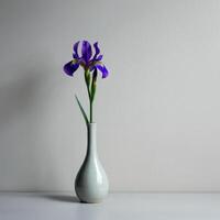 A striking purple iris in a minimalist ceramic vase dramatically lit to create a moody and artistic still life composition photo