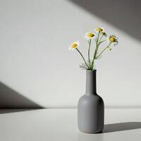 A single white daisy in modern dark gray ceramic vase, illuminated by moody lighting, creating an elegant and artistic still life composition photo