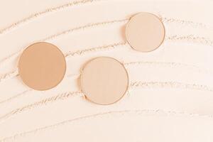 Three cosmetic blocks, a refill of different tones of compact powder on a light background of loose powder. Beautiful cosmetic background. layout photo