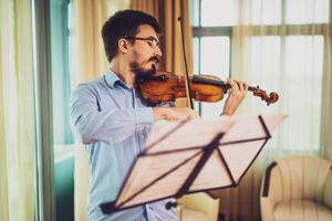 Man practicing violin at home. photo