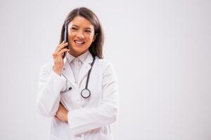 Studio shot portrait of cheerful and satisfied female doctor who is talking on phone with patient. photo
