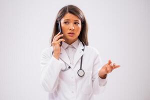 Portrait of worried female doctor who is talking on phone with patient. photo