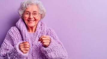 A Joyful Elderly Woman Dressed in a Cozy Sweater Posed Against a Vibrant Purple Background photo