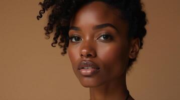 A person with curly hair stands in a neutral brown setting. photo
