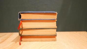 Stack of vintage books on a wooden table with a dark background video