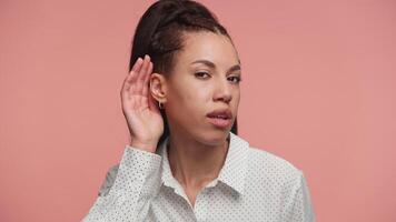 Curious woman trying to listen closely on pink background video