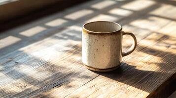 Handmade ceramic mug on weathered wooden table, bathed in soft morning light, creating warm and inviting atmosphere. shadows add depth and character to scene photo