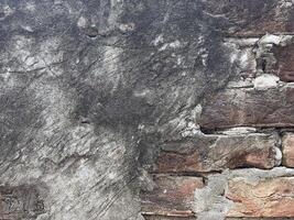 A close up of an Old Aged Damaged Brick wall with bad and crumbled plasterwork photo