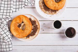 Bagel sandwich with butter and grated chocolate on a plate on a table top view photo