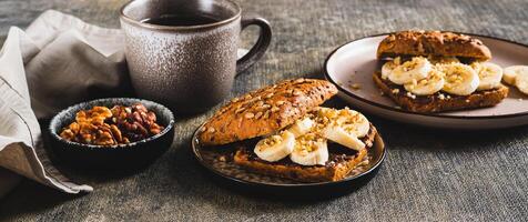 Sweet sandwich with chocolate butter, banana and nuts on a plate on the table web banner photo