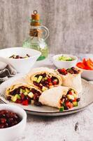 Salad of beans, cucumber and pepper in lavash rolls on a plate on the table vertical view photo