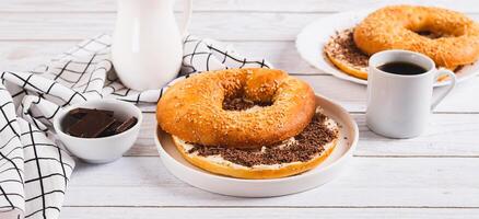 Bagel sandwich with butter and grated chocolate on a plate on a table web banner photo