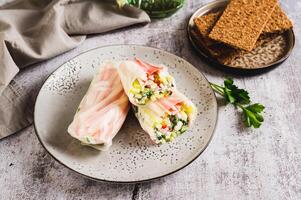 Spring rolls with crab meat, cucumber and herbs on a plate on the table photo