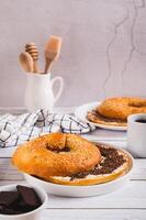 Bagel sandwich with butter and grated chocolate on a plate on a table vertical view photo
